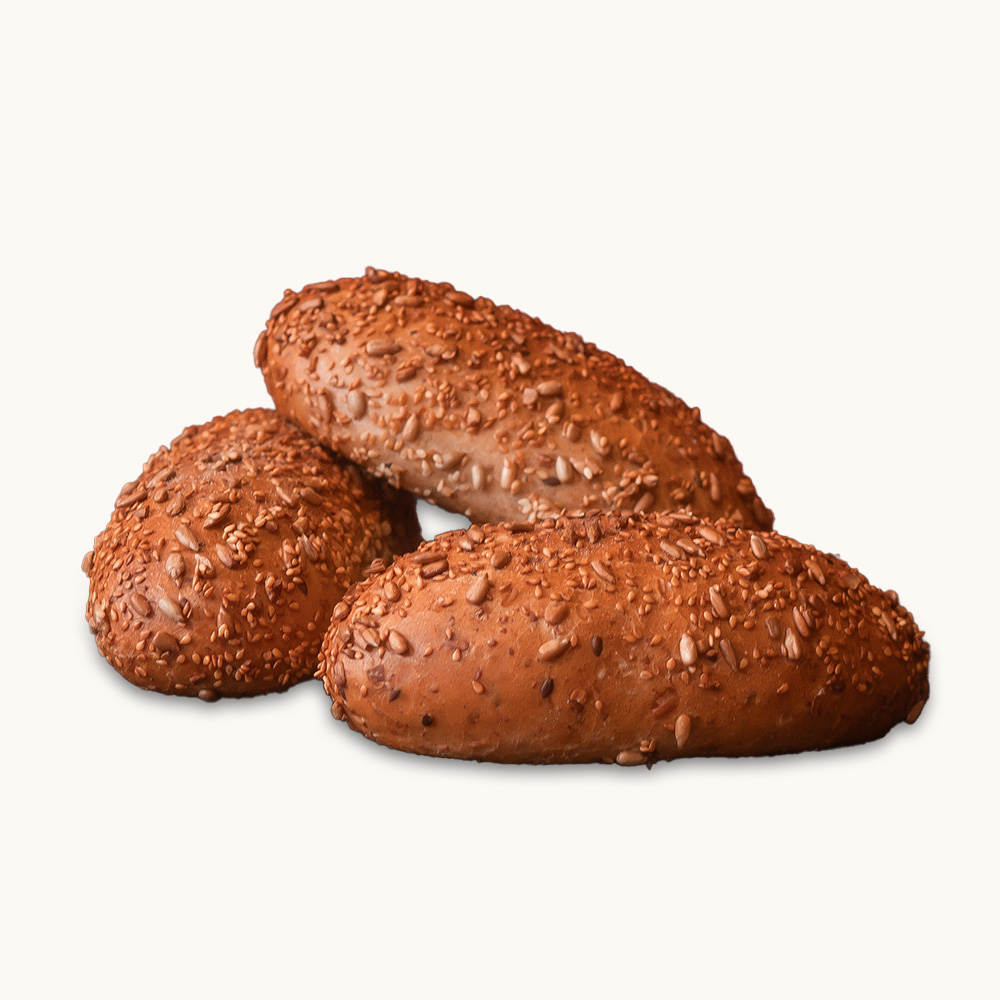 Drei Dinkelbrötchen mit goldbrauner Kruste und reichlich Körnern bestreut, auf hellem Hintergrund.