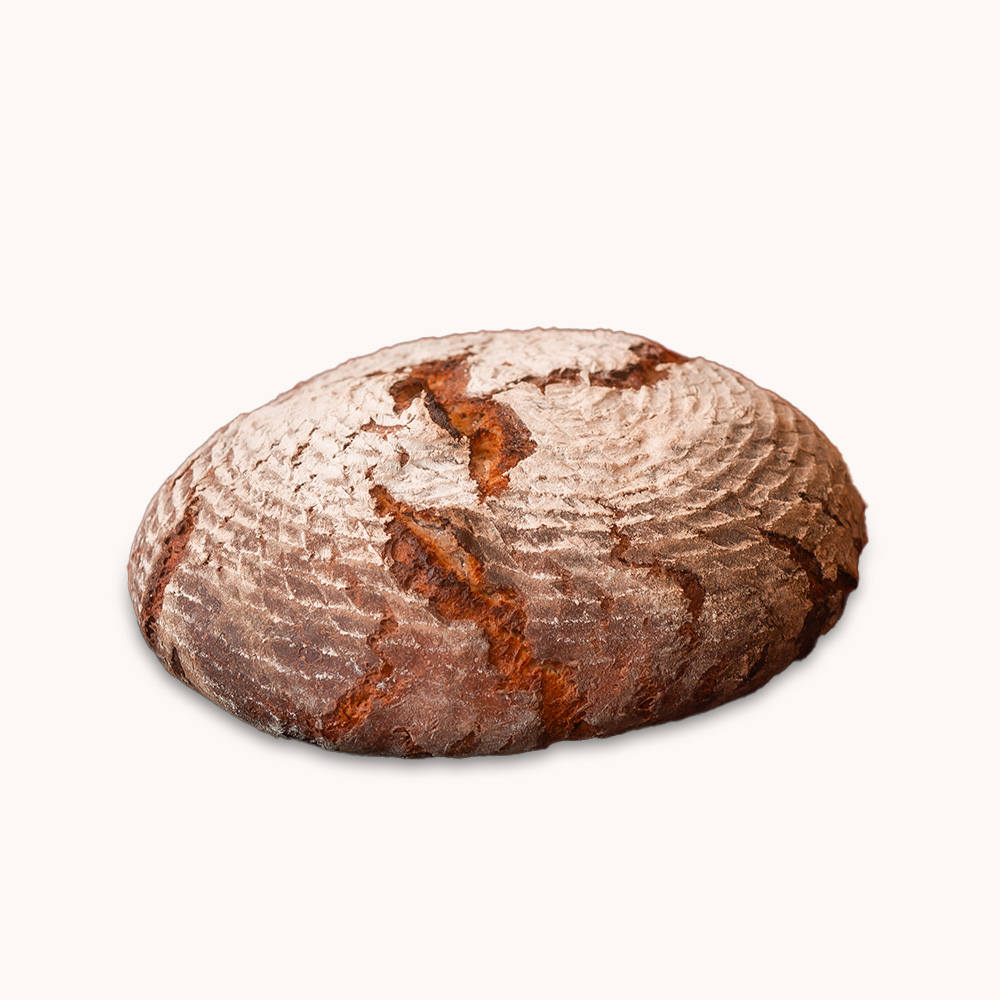 Rundes, rustikales Holzofenbrot mit kräftiger Kruste und bemehlter Oberfläche auf hellem Hintergrund.