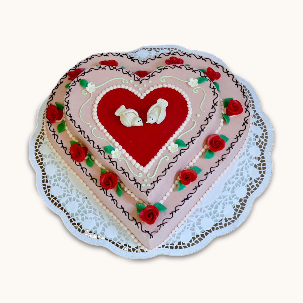 Herzförmige zweistöckige Hochzeitstorte mit rosa Fondant, roten Zuckerrosen und zwei weißen Tauben in der Mitte.
